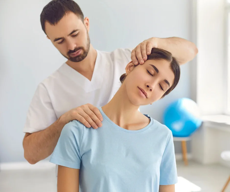 Osteopata in divisa bianca esegue una manipolazione cervicale a una paziente seduta